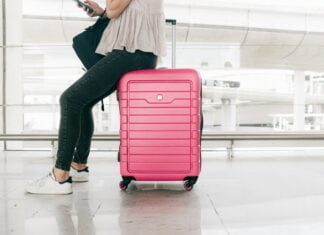 Woman-sitting-on-suitcase-in-airport_Travel-safe-during-covid-19