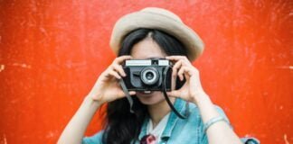 Anza What's On_Girl holding camera to her face red background