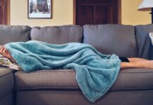Health-insurance-singapore-man-laying-under-towel-on-sofa