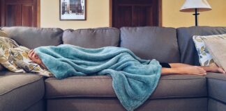 Health-insurance-singapore-man-laying-under-towel-on-sofa