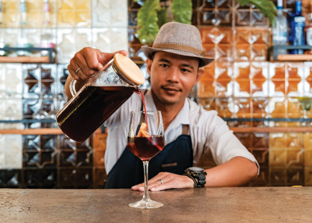 Bartender pouring sangria at stylish tiled bar.