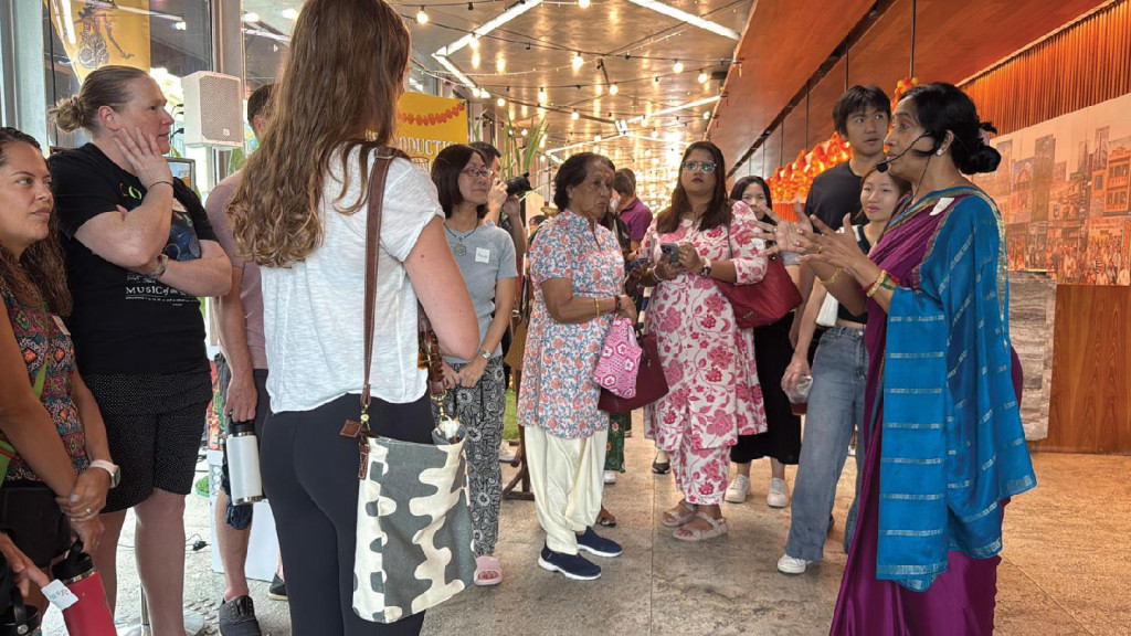 a group of people appears to be participating in a cultural or educational tour led by the woman in the sari, wearing a headset microphone