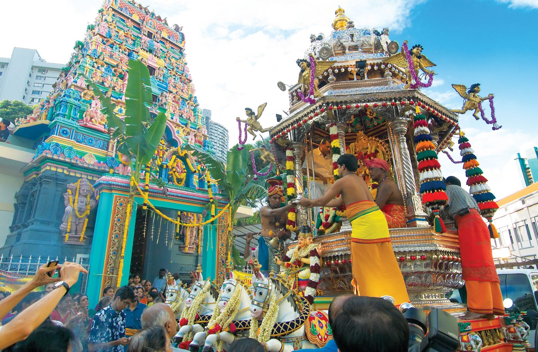 A Hindu temple chariot procession with a colorful temple in the background.