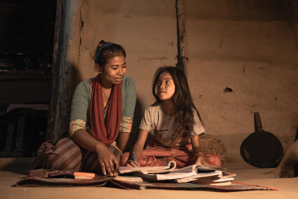 A mother and Daughter reading in low light in Nepal