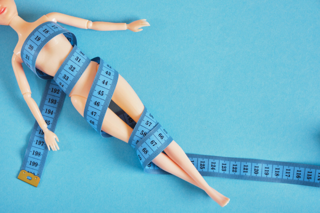 Barbie doll wrapped in measuring tape